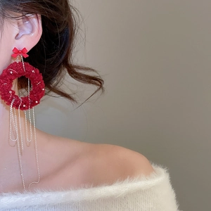 Close-up of red plush bow earrings with silver metal chain tassels on model