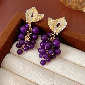 Macro shot of French vintage purple bead grape earrings with gold leaf and rhinestones