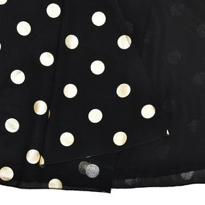 Dettaglio di elegante tessuto in chiffon nero con pois dorati lucidi e trama liscia