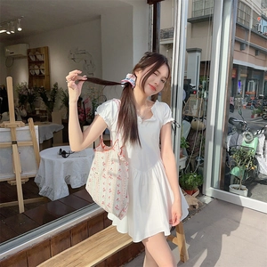 Pink floral canvas tote bag paired with a white puff sleeve dress in outdoor daylight