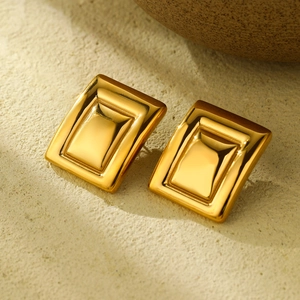 Macro view of gold-plated stainless steel square earrings with 3D geometric nesting