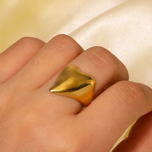 Golden heart-shaped wide open ring in polished stainless steel worn on a hand