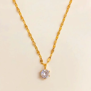 Detailed view of single round-cut zircon pendant with golden water-wave chain necklace