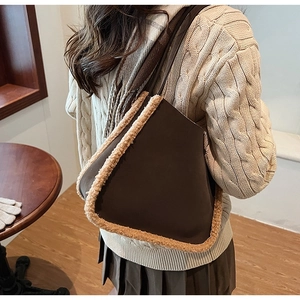 Detail of dark brown faux suede tote bag with plush shearling trim shown on shoulder