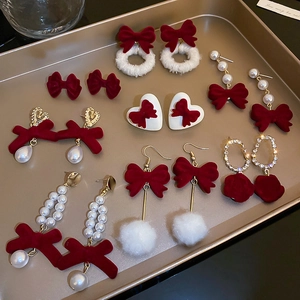 Detailed collection of red velvet bow earrings with pearls and rhinestones on a tray