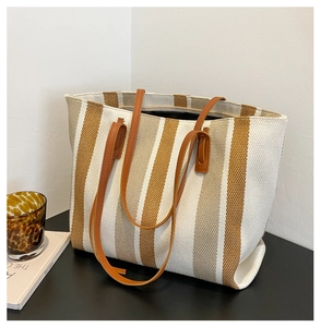 Detailed texture of the woven striped tote bag with high-quality brown leather handles