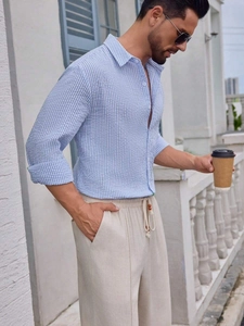 Detail of men's blue white striped seersucker shirt and beige linen drawstring pants