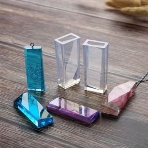 Dettaglio di ciondoli in resina geometrici e stampi in silicone su legno scuro