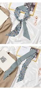 Detailed flat lay of silk scarf with blue and green geometric star patterns on a beige blazer