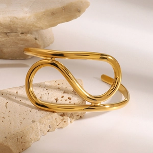 Minimalistisches goldenes geometrisches Armband präsentiert auf beigem Naturstein Sockel