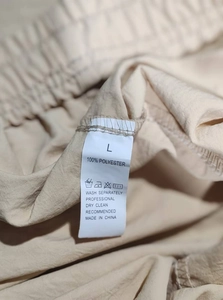 Detailed close-up of the size L wash label and 100% polyester fabric texture