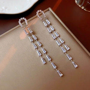 Detail of silver tassel earrings with baguette-cut zircons and U-shaped micro-pave studs