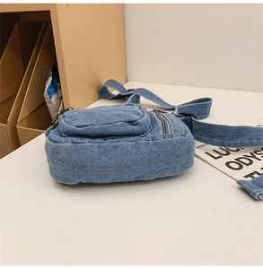 Close-up of blue denim crossbody bag with front pocket and adjustable shoulder strap