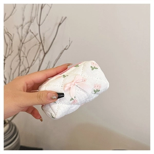Close-up of quilted floral cotton mini makeup pouch with pink bow and zipper detail