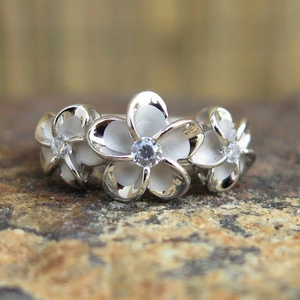 Macro shot of silver flower ring featuring three frosted petals with zircon centers