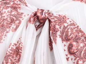 Vista dettagliata del nodo al collo e del motivo paisley sul tessuto dell'abito in chiffon