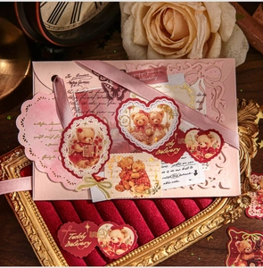 Close-up of vintage Teddy Bear stickers with pink hollow envelope on red velvet display