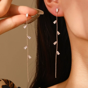 Macro detail of long gold tassel earrings with sparkling rectangular cubic zirconia