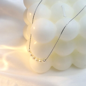 Elegant silver 18k titanium steel necklace with 7 pearls draped over decor