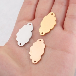 Three mirrored stainless steel cloud pendants in silver, gold and rose gold on a palm