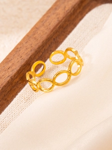 Macro shot of gold-plated linked hollow oval rings on textured beige fabric
