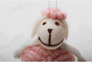 Close-up of pink handmade wool felt sheep pendant with cute knitted texture for Christmas
