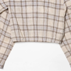 Fashionable beige plaid cropped top with elastic hem and long sleeves on white background