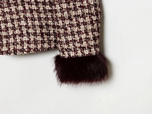 Detail of red tweed blazer showing faux fur cuffs and houndstooth fabric texture