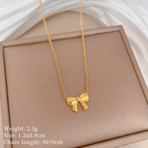 Macro view of gold bow pendant with measurements 1.2x0.9cm on beige display board
