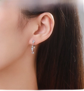 Close-up of S925 silver earrings with pink, blue, and opal gemstones on female ear