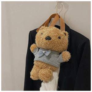 Detail of a plush brown teddy bear bag with grey T-shirt and blue bow on black blazer