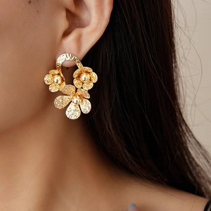 Gros plan de boucles d'oreilles fleurs dorées martelées pour un look vintage élégant
