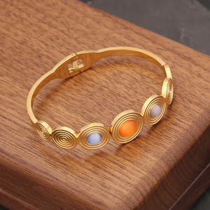 Detail of vintage gold bangle with cat eye stones and side hinge on wooden box
