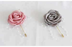 Détail de la boutonnière rose en satin avec perles élégantes et épingle dorée pour mariages