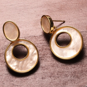 Detail of 18K gold-plated round earrings with beige shell-like resin and hollow design