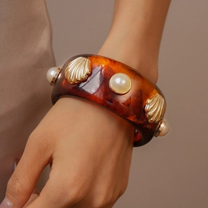 Macro detail of vintage resin bangle with golden seashells and white pearls