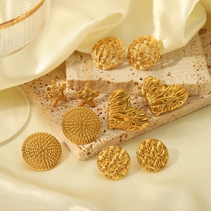Vue détaillée de boucles d'oreilles géométriques dorées sur tissu de soie élégant