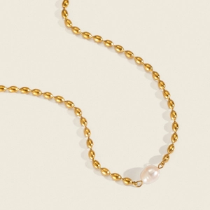 Close-up of a gold rice chain necklace featuring an irregular baroque pearl drop