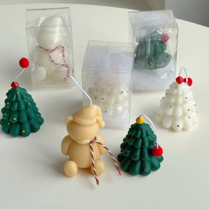 Close-up of mini Christmas tree and bear scented candles in transparent gift packaging