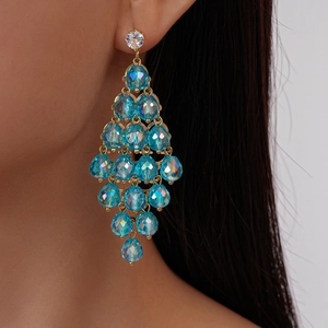Close-up of gold chandelier earrings with blue faceted crystal beads worn by a female model