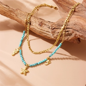 Gold ocean charms necklace with turquoise beads featuring seahorse and starfish pendants