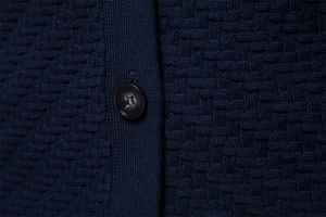 Detailed view of navy blue knit fabric and black button on men's V-neck cardigan