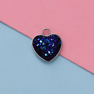 Macro detail of heart-shaped stainless steel pendant with dark blue glitter inlay