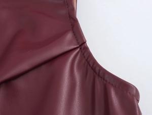 Detailed close-up showing stitching and texture of dark red faux leather vest and shorts