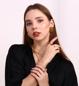 Close-up of gold 18K plated geometric rectangular stud earrings and layered snake chains