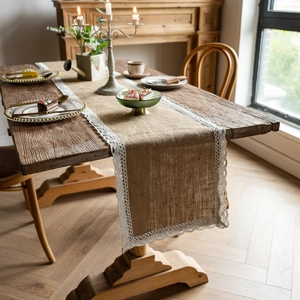 Natural jute table runner with white lace edges on a rustic wooden dining table
