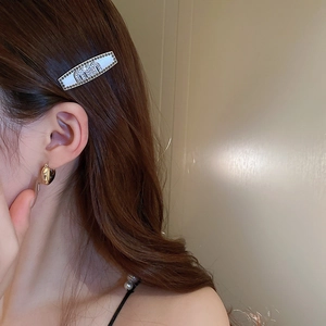 Silver Y2K star hair clip with rhinestone Miu lettering and heart earring on a model
