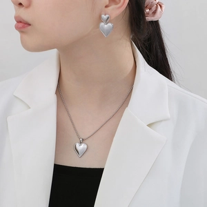 Polished silver heart pendant necklace and matching earrings set on model