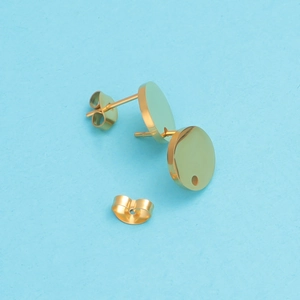 Detail of round gold stainless steel earring studs with butterfly backings on blue background