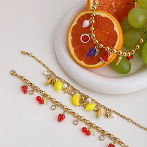Detail of 18K gold-plated bracelets featuring colorful fruit charms and small pearls